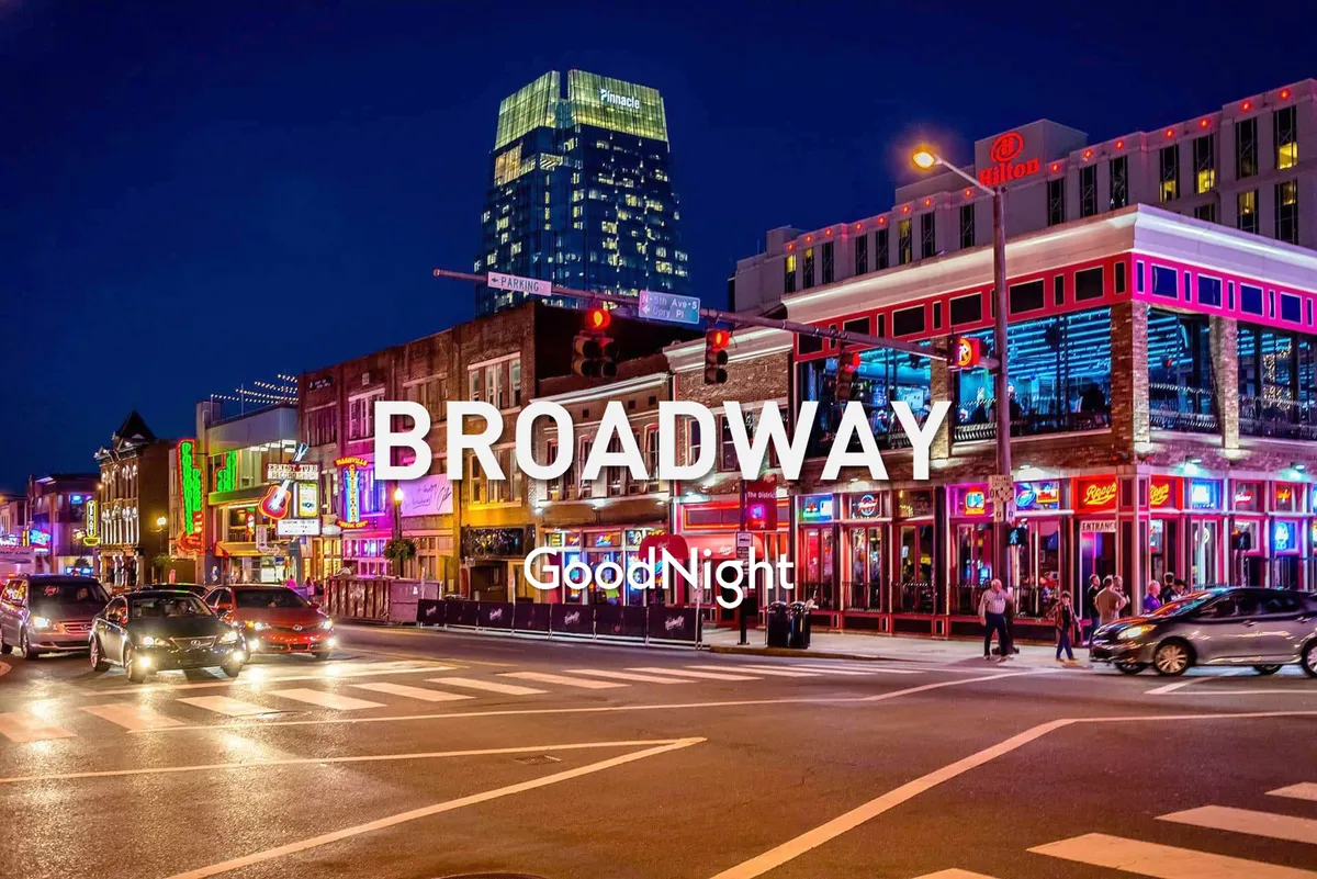 A bustling Midtown Nashville street scene at night, complete with neon signs, high-rise buildings, pedestrians, and cars. The energy of live music venues, restaurants, and nightlife is palpable, showcasing the area’s vibrant urban culture.
